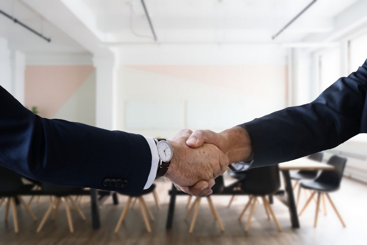 two men in suits engage in a handshake