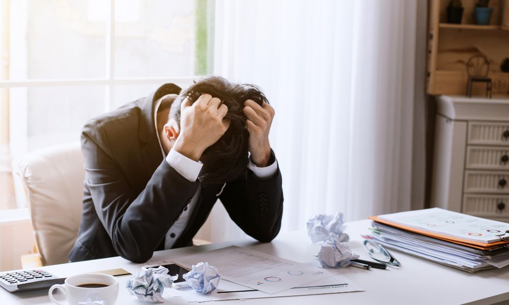 A male office worker fists his hands into his hair, he's very stressed - for blog: one market businesses
